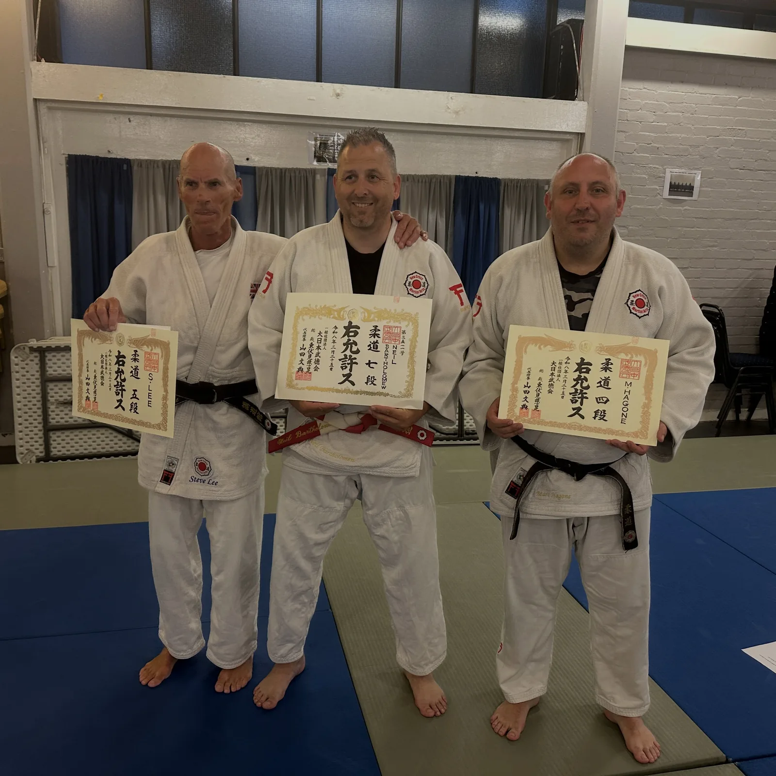 Neil Bartholomew (centre) with his DNBK 7th Dan certificate, June 2026